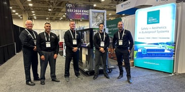 Group of five men wearing black uniforms standing in front of trade show booth