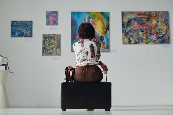 A woman studies paintings in an art gallery, illustrating the need to protect people people and assets as part of effective museum security. 