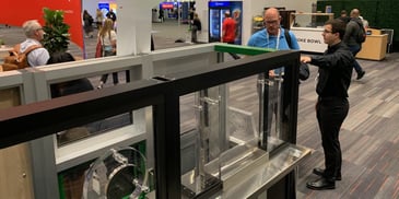 Two men speaking near bulletproof barrier display